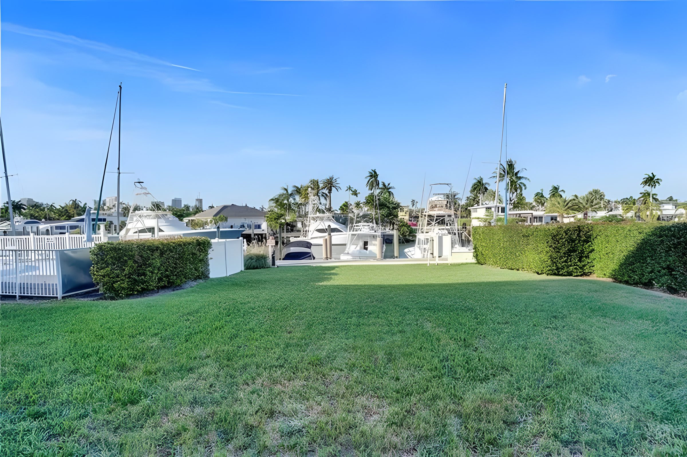 The lawn between the building and the dock, with masts and the seawall beyond.